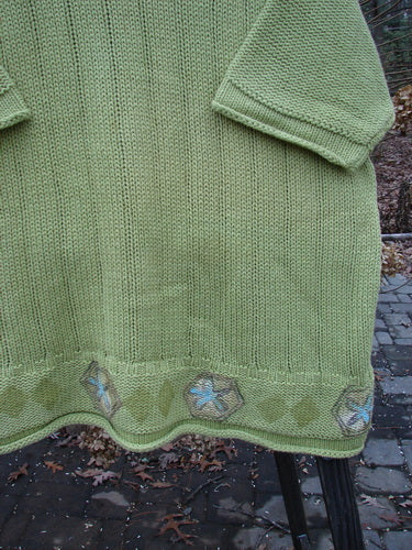 1999 Spring Pullover Tunic Sweater Kiwi Size 2: A green sweater with a pattern, varied textures, and knit details. A-line shape with drop shoulders and rolled sleeves.