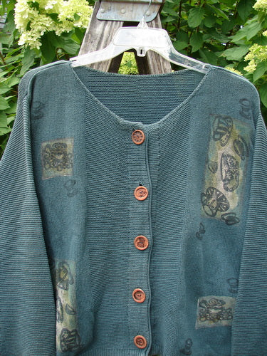 1994 Panel Cardigan Sweater Magic Tea Party Nightshade OSFA displayed on a plastic hanger, with wooden buttons, patch designs, and belled sleeves, reflecting vintage Blue Fish Clothing's creative, expressive ethos.