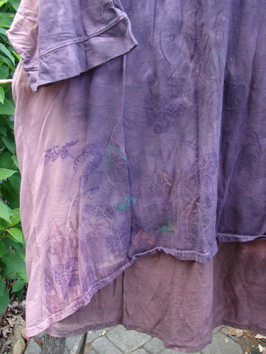 Barclay Banded Drawcord Art Top Paisley Patch Mottled Plum OSFA features a longer tunic length, rounded neckline, and loose three-quarter sleeves, showcasing a unique upward rounded front hem and tiny village-themed paint.