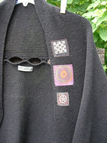 Barclay Patched Alpaca Rear Window Shrug in Black OSFA, featuring distinctive fabric appliqués and teardrop buttonholes, gracefully draped outdoors, embodying Bluefishfinder.com's unique vintage style and creative freedom.