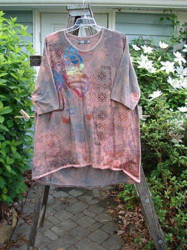 Barclay Tournesol Tunic Butterfly Love Mottled Sunset OSFA: A tunic-length, organic cotton top with drop shoulders, three-quarter sleeves, rounded neckline, and varying hemline, featuring 2023 theme paint and generous measurements.