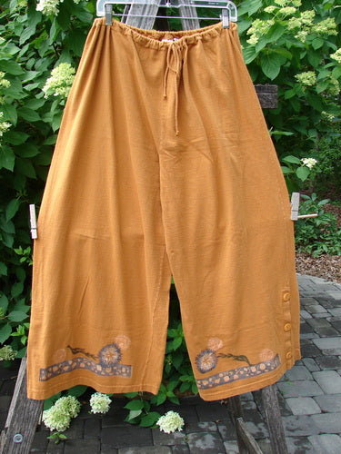 1994 Banjo Pant Dandelion Breeze Oro Size 2, featuring loose-fitting, wide-leg trousers with elastic drawstring waist and floral motif band on hem, accentuated with three fabric-covered buttons near the ankle.