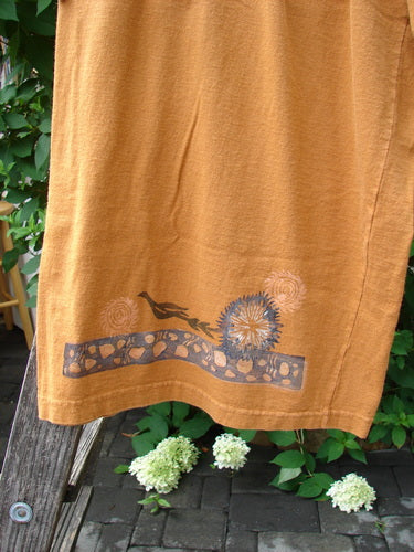 1994 Banjo Pant Dandelion Breeze Oro Size 2 draped over a wooden ladder outdoors, showcasing the intricate Magic Curly Garden-themed hem design with stylized bird and floral motifs, against a backdrop of green foliage.