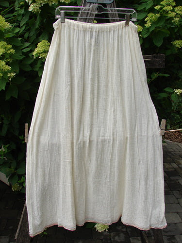 1998 Gauze Under Skirt Unpainted Cloud Size 2: A long, airy white skirt made from lightweight cotton-gauze fabric with a delicate silk ribbon hem, hanging outdoors, showcasing its flowing A-line shape.