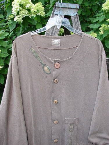 1999 Silverware Top Reverse Dining Riverbed OSFA: A taupe button-up top with mismatched buttons, spoon-and-fork graphics, hanging on a trellis. Features pencil pockets and a blue fish signature patch.