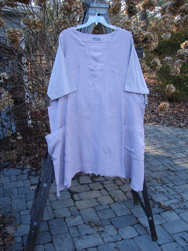 Barclay Linen Cotton Sleeve Triangle Dress on a rack, with an empire waist seam, drop side pockets, and longer cotton sleeves. Size 2, lavender.
