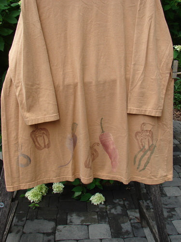 1998 Vegetable Tunic Top Bountiful Garden Ochre Size 2 hanging on a metal rack, featuring a softly scooped neckline and stenciled vegetable motifs along the hem, made from organic cotton jersey.