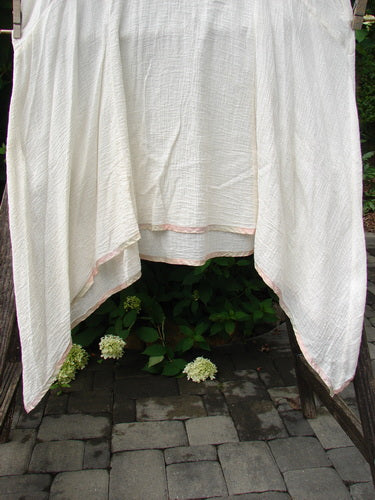 1998 Gauze Over Dress Silk Ribbon Unpainted Chalk Size 2, draped on a wooden frame outdoors, showcases lightweight cotton gauze with hand-dyed silk rainbow ribbon edging, highlighting its versatile, airy design.