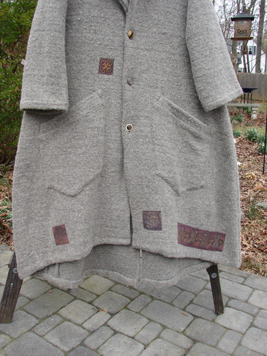 Vintage wool Cormac coat with pockets on a rack, stone walkway close-up.