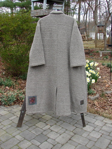 Vintage wool coat with Celtic patch details, hanging on a rack.