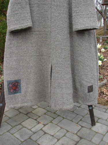 Vintage wool coat with patchwork design on rack, close-up stone walkway detail.
