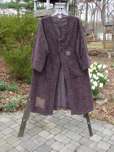 Patched Upholstery Diwmach Coat on rack, tree branch, flower, tree, stone walkway, and ramp.
