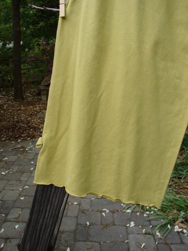 Barclay Crop Tiny Tab Pant in Sunshine, Size 2. A yellow sheet hangs on a clothesline, with a close-up of a yellow towel. A black rectangular object rests on a brick surface.