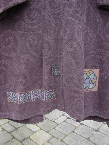 Patched upholstery coat with Celtic designs and fabric textures.