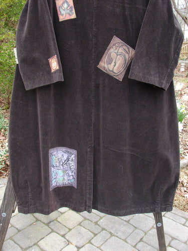 Vintage coat with patches, close-up details of tapestry, sleeve repair spot, outerwear fashion.