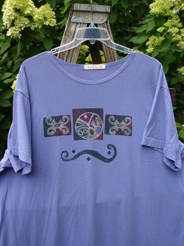 The 1997 Aquavella Dress Celtic Trio Skylark Size 2 features abstract graphics on a soft purple-lavender T-shirt, showcasing a unique design that aligns with BlueFishFinder's vintage, expressive style.
