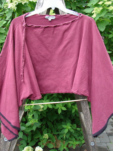 Barclay Cotton Lycra Contrast Crop Shrug Deep Celtic Curl Wine Size 2 draped over a light wooden ladder, showcasing its wide kimono-like sleeves, laced neckline, and contrast banded accents, embodying vintage Blue Fish style.