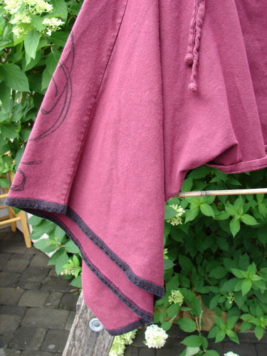 Barclay Cotton Lycra Contrast Crop Shrug Deep Celtic Curl Wine Size 2 draped over wood, showcasing black-trimmed hem, braided drawcord, and black swirl pattern, embodying Celtic charm from Bluefishfinder.com's vintage collection.