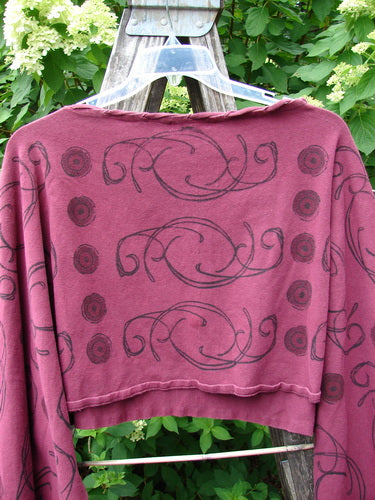 Barclay Cotton Lycra Contrast Crop Shrug Deep Celtic Curl Wine Size 2, featuring a wine hue with black swirls and floral motifs, belled sleeves, and laced neckline, hung on a plastic hanger.