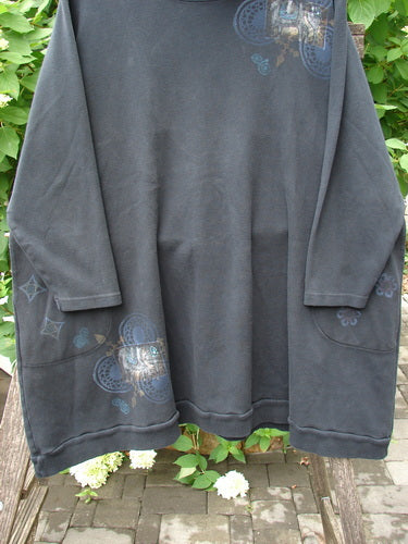 Barclay Interlock Turtleneck Pullover Tunic Top Celtic Night Black Size 2, featuring a ribbed turtleneck, front patch pockets, and blue-gray heart-and-floral stencil prints on the lower panels and shoulders.