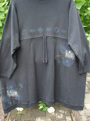 Barclay Interlock Turtleneck Pullover Tunic Top Celtic Night Black Size 2, featuring a loose fit, three-quarter sleeves, drawstring waist, and blue-gray mandala prints, draped over a railing.