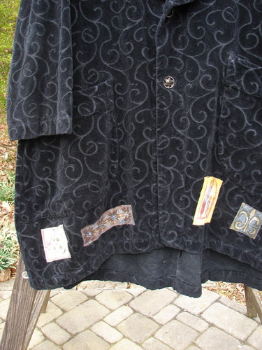 Patched Poet's Coat with swirl design, stone walkway close-up, wood post detail.