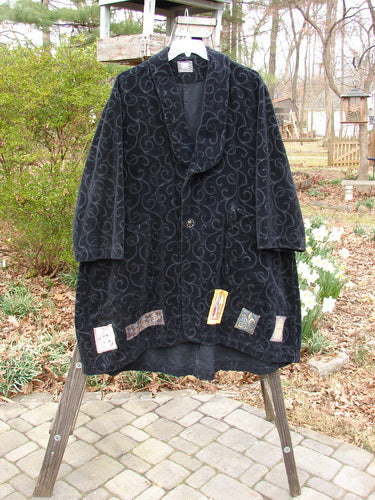Patched Poet's Coat hanging on rack, close-up of flower, stone walkway, outdoor setting.