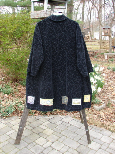Patched Poet's Coat with swirl design on rack.