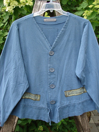 1997 Treehouse Jacket Greek Column Blueprint Size 2, featuring a light-blue color with a V-neck, four large buttons, decorative pocket flaps, and a drawcord flounce, displayed on a hanger outdoors.