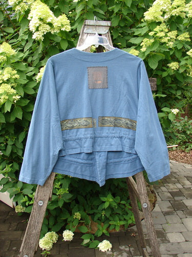 1997 Treehouse Jacket Greek Column Blueprint Size 2 hangs on a wooden ladder, showcasing its boxy, cropped style with a decorative ribbon at the waist, V-neck design, and signature Blue Fish patch.