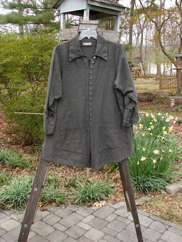 Barclay Linen Metal Button Drop Pocket Pullover Unpainted Grey Storm Altered Size 2, displayed on a wooden hanger, showcasing metal button accents, double drop front pockets, and billowy cuffed sleeves.