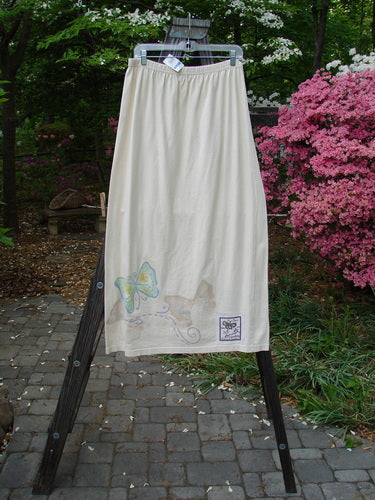 1999 NWT Straight Skirt Butterfly Natural Size 2: A white skirt adorned with butterfly-themed paint all around the hem, hanging on a clothes rack.