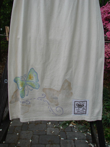1999 NWT Straight Skirt Butterfly Natural Size 2: A white towel with a butterfly design, perfect for summer. Made from organic cotton, it features a full elastic waistband and a straight shape. The butterfly theme is beautifully painted all around the hem.