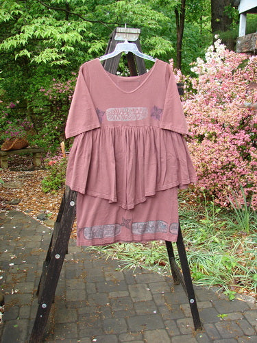 1993 Picnic Dress Fern Boysenberry OSFA: A pink dress on a rack with a flirty continuous flounce, fern and flower theme paint, and a vintage signature patch.