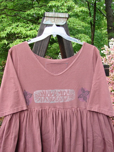 Image alt text: 1993 Picnic Dress featuring a pink shirt on a swinger, adorned with a fern and flower theme paint and a vintage signature patch.