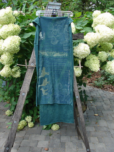 Barclay Wide Sectional Scarf Wrap Forest Animals Mottled Green OSFA drapes from a wooden ladder, showcasing marine motifs with neat curly edges, in a lush garden setting. Perfect for shawl use.