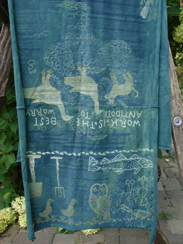 Barclay Wide Sectional Scarf Wrap Forest Animals Mottled Green OSFA displayed on a wooden bench, featuring stylized hares, trees, and garden tools, embodying a folk-art feel with motivational quotes.