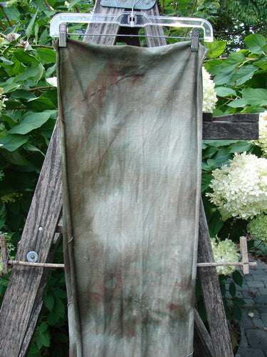 Barclay Diagonal Sectional Scarf Wrap Unpainted Mottled Night Storm OSFA displayed on a wooden frame, showcasing its curly edges and diagonal seams against a garden backdrop.