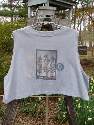 1994 Spruance Vest Topiary Solstice Blue OSFA displayed on a clothes rack, showcasing its unique crop layering length and wide A-line flare with a topiary-themed rear print and dual paper button closure.