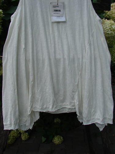 Magnolia Pearl NWT Cotton Paz Tank White OSFA displayed outdoors on a hanger, features raw edges, a widening shape, and hand distressing, with a retail tag visible at the neckline.