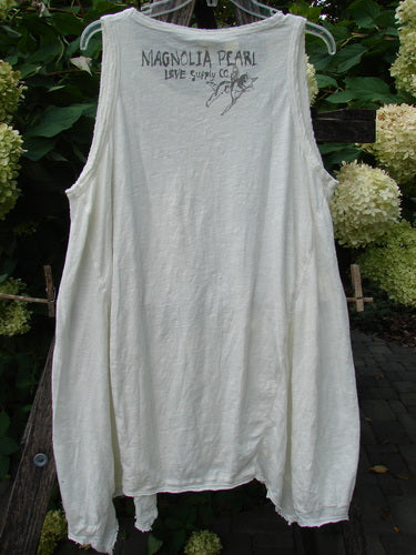 Magnolia Pearl NWT Cotton Paz Tank White OSFA, featuring raw edges, a widening shape, and A-line flare, displayed outdoors. Signature logo on the back, embodying vintage-inspired, artistic flair from Bluefishfinder.com.