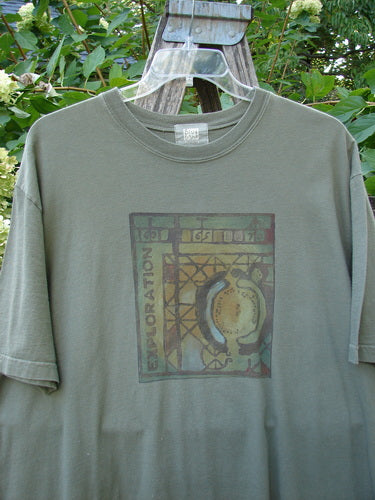 2000 Short Sleeved Tee Celtic Exploration Park Size 2, featuring a square graphic with horseshoe shapes and EXPLORATION text. Displayed outdoors, it has drop shoulders and a thicker ribbed neckline.