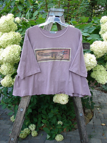 Barclay PMU Patched Short Sleeved Crop A Line Tee Dark Mallow Size 2, featuring a boxy silhouette, wide neckline, elbow-length sleeves, and an alligator-themed patch, displayed on a wooden ladder outdoors.