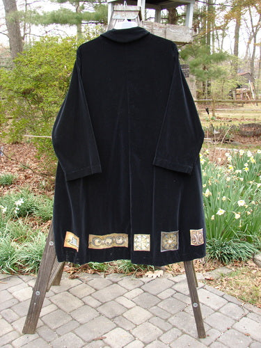 1999 Velveteen Poet's Coat Holiday Celtic Black Size 1 on a rack, featuring oversized pockets, vintage buttons, and colorful patches, showcasing Bluefishfinder.com's unique vintage collection.
