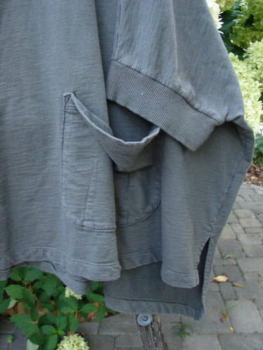 Barclay Slub Dolman Shirttail Pocket Jacket Fern Green Army Size 0 draped over a branch, showcasing its ribbed cuffs, pouch pocket, and dolman drop seamless shoulders against a natural outdoor backdrop.