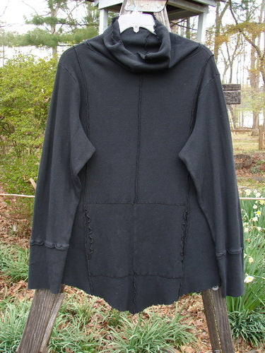 Barclay Light Weight Thermal Cowl Neck Roo Tunic Unpainted Black Size 1 displayed on a wooden pole, featuring a hood, exterior stitchery, curly edgings, ribbed cuffs, and a kangaroo pocket.