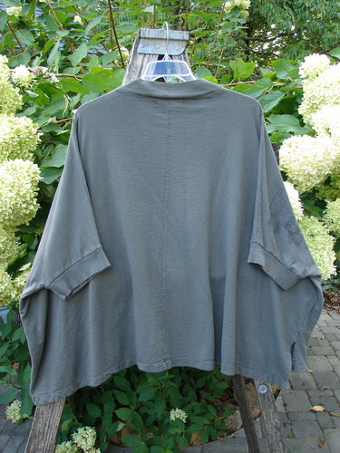 Barclay Slub Dolman Shirttail Pocket Jacket in Fern Green Army is draped over a step ladder. It showcases dolman sleeves, a ribbed collar, and a distinctive shirttail hemline.