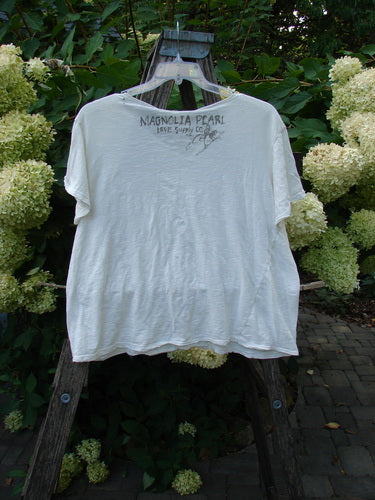 Magnolia Pearl NWT Cotton Europa V Neck Boyfriend Tee True White OSFA hangs on a wooden stepladder, showcasing its super soft, drapey feel with raw edges and a feminine V-shaped neckline.