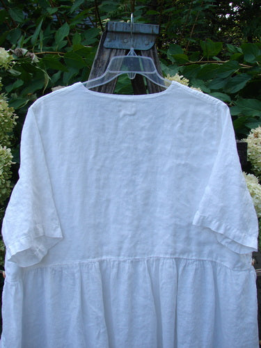 1999 Linen Adjustable Wrap Dress Fish White OSFA: Loose-fitting white linen smock-style dress with short sleeves, gathered waist, flared skirt, displayed on a hanger outdoors against green foliage background.