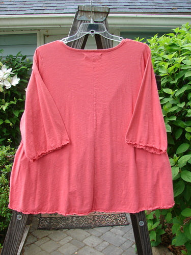 Image alt text: Barclay Three Quarter Sleeved Textured A Lined Tee Top Hail Geranium Size 2 - A pink shirt with a textured pattern and three-quarter sleeves, featuring a rounded neckline and curly edgings.